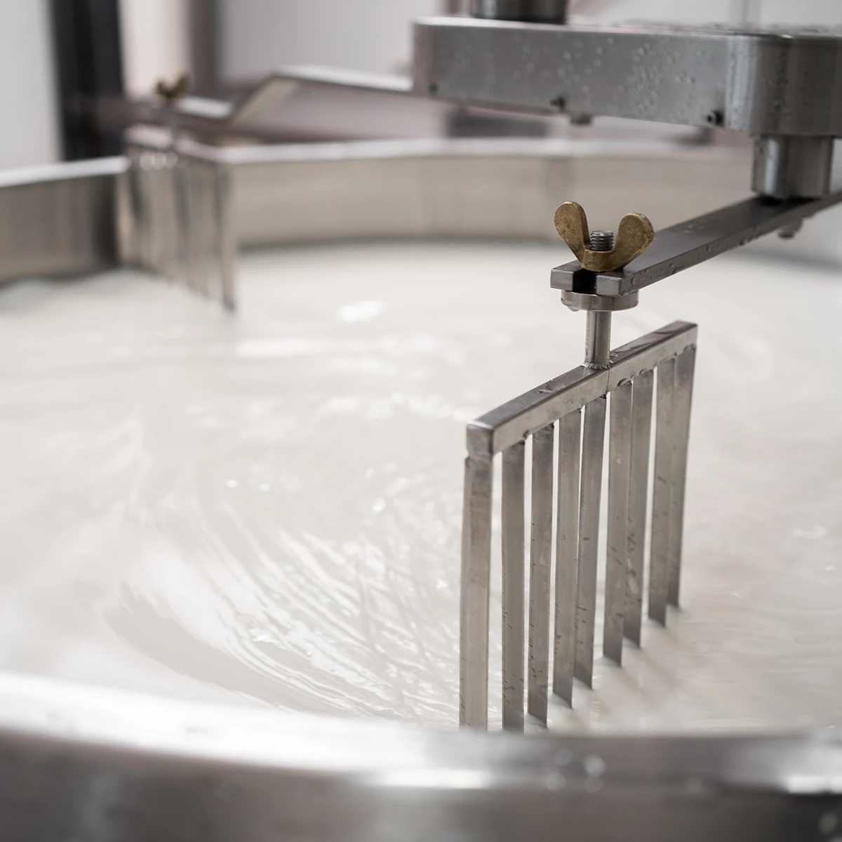 Close up of the automated machine used for stirring a vat of milk
